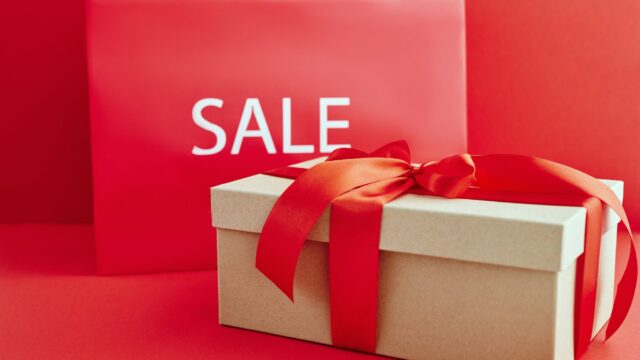 cardboard box with red ribbon beside a sale sign